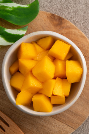 Fresh chopped, diced mango cubes on gray table background with tropical leaf for eating.の写真素材