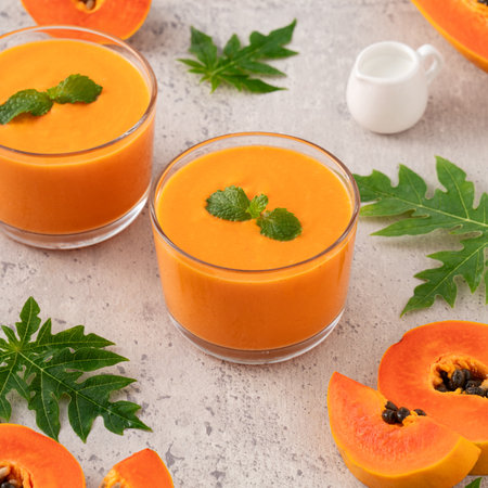 Fresh delicious papaya milk smoothie in glass cup on gray table background for tropical fruit design concept.の写真素材
