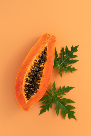 Cut Papaya over orange table background for tropical fruit design concept, top view copy space.の写真素材
