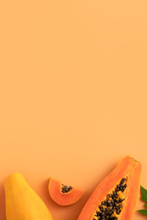 Cut Papaya over orange table background for tropical fruit design concept, top view copy space.の写真素材
