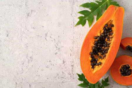 Cut Papaya over gray table background for tropical fruit design concept, top view copy space.の写真素材