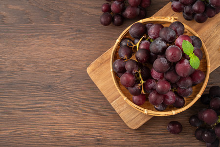 Delicious bunch of purple grapes fruit on a plate on wooden table background.の写真素材