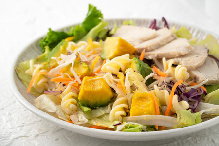 Fresh avocado lettuce salad bowl with sliced chicken meat and rotini on a plate on white table background.の写真素材