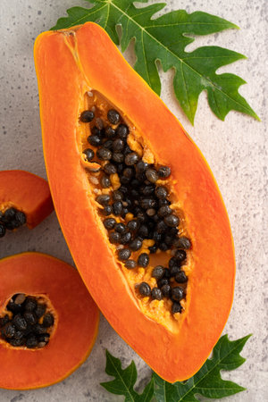 Cut Papaya over gray table background for tropical fruit design concept, top view copy space.の写真素材