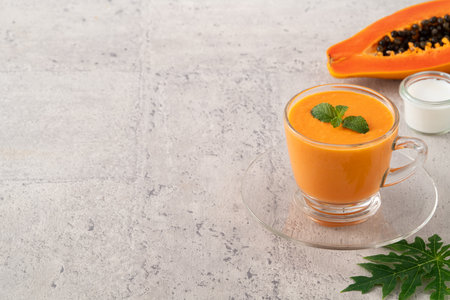 Fresh delicious papaya milk smoothie in glass cup on gray table background for tropical fruit design concept.の写真素材