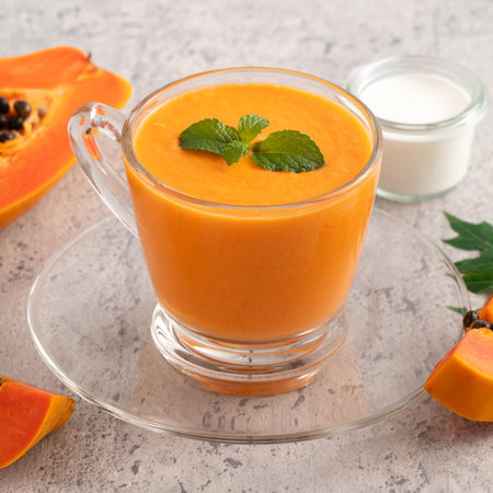 Fresh delicious papaya milk smoothie in glass cup on gray table background for tropical fruit design concept.の写真素材