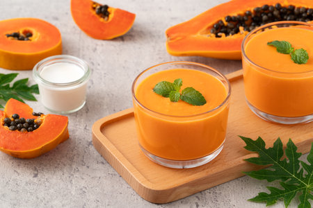 Fresh delicious papaya milk smoothie in glass cup on gray table background for tropical fruit design concept.の写真素材