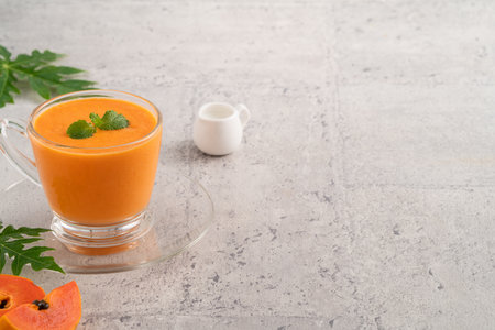 Fresh delicious papaya milk smoothie in glass cup on gray table background for tropical fruit design concept.の写真素材