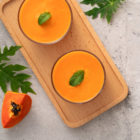Fresh delicious papaya milk smoothie in glass cup on gray table background for tropical fruit design concept.の写真素材