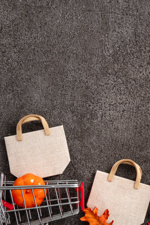 Autumn shopping design concept with shopping cart, maple leaves and pumpkin on black table background.の写真素材