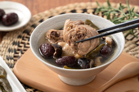 Delicious Taiwanese peeled green chili pepper chicken soup with mushroom in a bowl on wooden table background.の写真素材