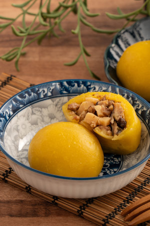 Homemade sweet potato yam bun with ground pork meat, mushroom and chopped bamboo shoot fillings inside in a bowl on wooden table background.の写真素材