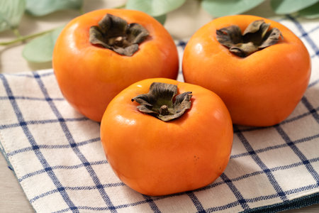 Fresh ripe sweet persimmon kaki fruit on wooden table background.の写真素材