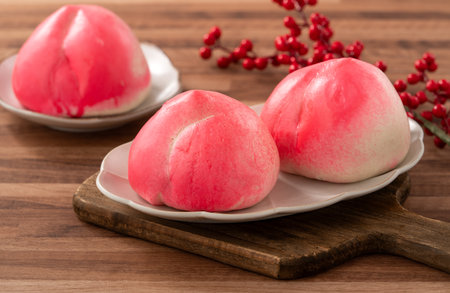 Pink Chinese peach birthday bun food longevity peach shoutao on wooden table background.の写真素材