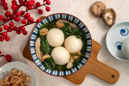 Eating big tangyuan yuanxiao, tang yuan, glutinous rice dumpling balls, with savory vegetable soup in a bowl for Winter solstice festival.の写真素材