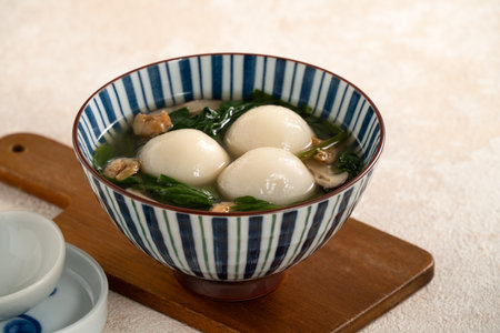 Eating big tangyuan yuanxiao, tang yuan, glutinous rice dumpling balls, with savory vegetable soup in a bowl for Winter solstice festival.の写真素材