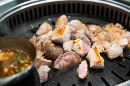 Grilling pork meat on an iron BBQ board in Korean restaurant, fresh delicious food cuisine lifestyle.の写真素材