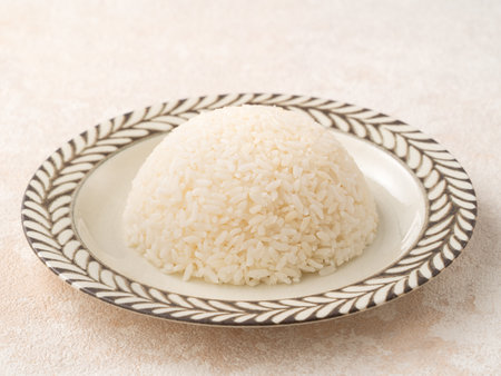 A bowl of freshly cooked steamed white rice, soft, fluffy, and slightly glossy on white table background.の写真素材