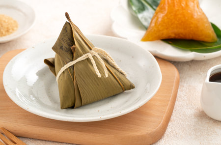 Golden alkaline zongzi rice dumpling served on a leaf, a classic treat for the Dragon Boat Festival.の写真素材
