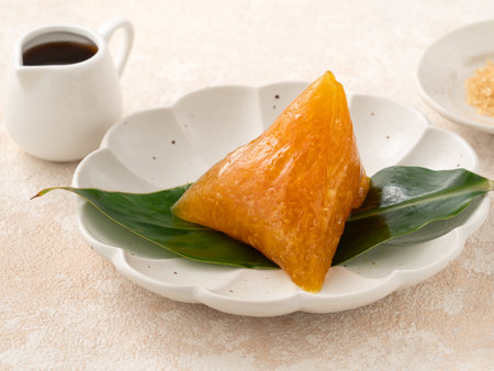 Golden alkaline zongzi rice dumpling served on a leaf, a classic treat for the Dragon Boat Festival.の写真素材