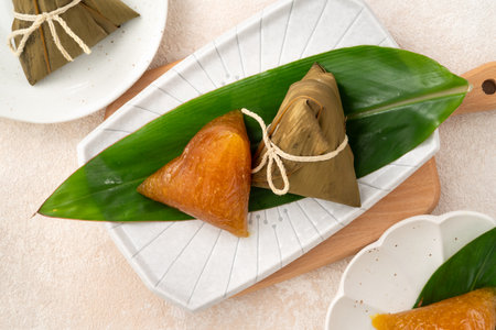 Golden alkaline zongzi rice dumpling served on a leaf, a classic treat for the Dragon Boat Festival.の写真素材