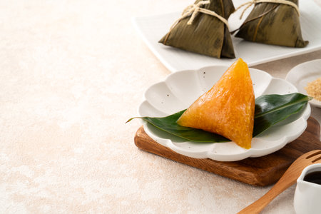 Golden alkaline zongzi rice dumpling served on a leaf, a classic treat for the Dragon Boat Festival.の写真素材