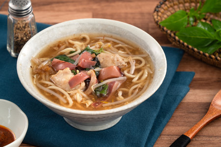 Traditional Taiwanese squid noodle soup with thick broth, served in a ceramic bowl on wooden table.の写真素材