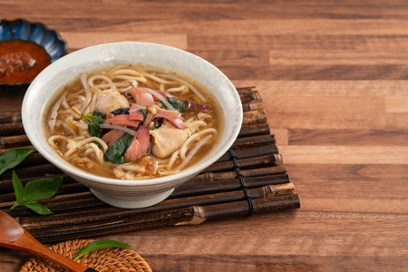 Traditional Taiwanese squid noodle soup with thick broth, served in a ceramic bowl on wooden table.の写真素材