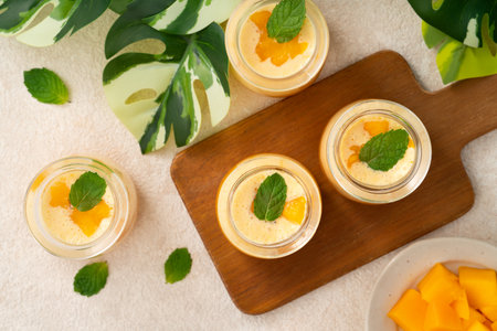 Refreshing mango mousse dessert served in glass cups, topped with mint leaves, perfect for summer.の写真素材