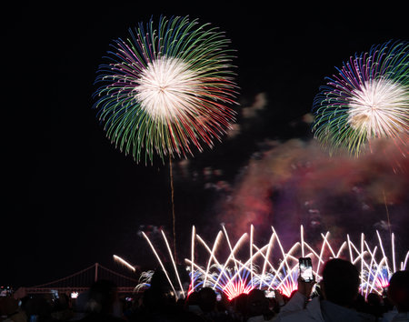 Brilliant fireworks burst above a crowd during a dazzling nighttime celebration near a bridge in busan korea.の写真素材