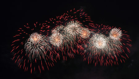 Brilliant fireworks burst above a crowd during a dazzling nighttime celebration near a bridge in...