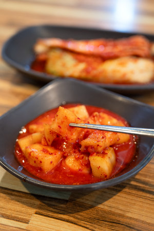 Close-up of cubed radish kimchi served in a black dish, traditional Korean gourmet side dish.の写真素材