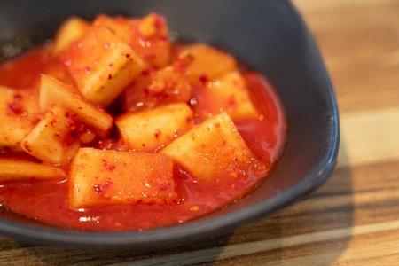 Close-up of cubed radish kimchi served in a black dish, traditional Korean gourmet side dish.の写真素材