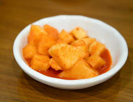 Close-up of cubed radish kimchi served in a black dish, traditional Korean gourmet side dish.の写真素材