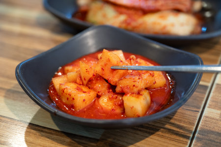 Close-up of cubed radish kimchi served in a black dish, traditional Korean gourmet side dish.の写真素材