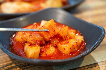 Close-up of cubed radish kimchi served in a black dish, traditional Korean gourmet side dish.の写真素材