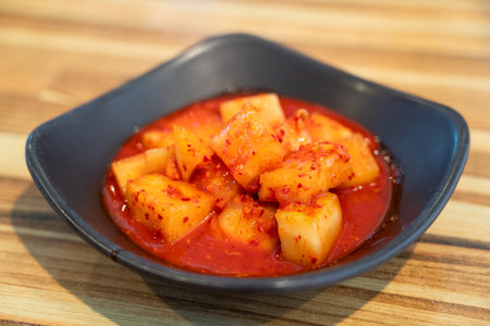 Close-up of cubed radish kimchi served in a black dish, traditional Korean gourmet side dish.の写真素材