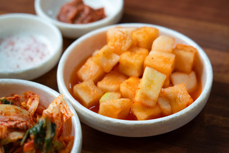 Close-up of cubed radish kimchi served in a black dish, traditional Korean gourmet side dish.の写真素材