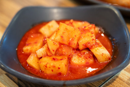 Close-up of cubed radish kimchi served in a black dish, traditional Korean gourmet side dish.の写真素材