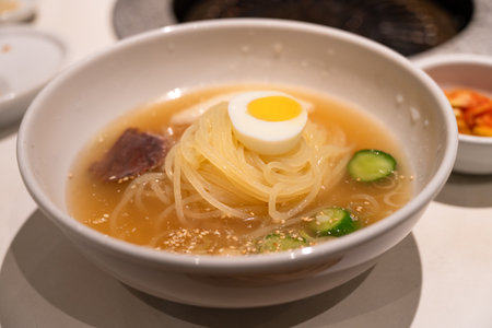 Refreshing Korean cold noodles served in chilled broth with sliced vegetables and boiled egg.の写真素材