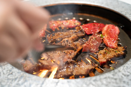 Marinated beef meat slices being grilled in BBQ restaurant.の写真素材