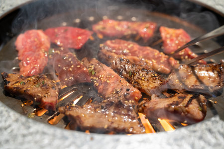 Marinated beef meat slices being grilled in BBQ restaurant.の写真素材