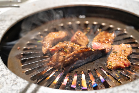 Marinated beef meat slices being grilled in BBQ restaurant.の写真素材