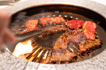 Marinated beef meat slices being grilled in BBQ restaurant.の写真素材