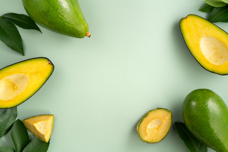Whole and sliced avocados with diced pieces over green table background.