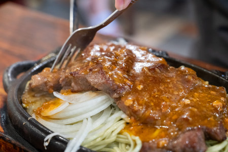Taiwanese style special hot sizzling beef steak with noodles, egg and sauce on an hot iron board plate.の写真素材