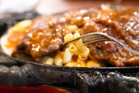 Taiwanese style hot sizzling beef steak with noodles, egg and sauce on an iron board plate.の写真素材