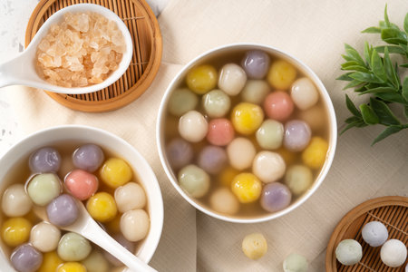 Traditional Asian sweet soup with colorful glutinous rice balls tangyuan served in warm sweet ginger syrup in white Terrazzo backgroundの写真素材