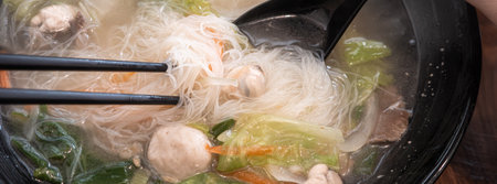 A bowl of Taiwanese rice noodles with mixed seafood and vegetables in clear savory broth.