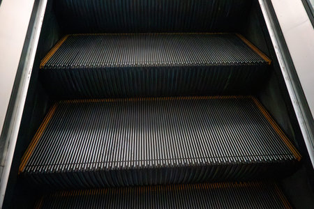 A clean metal escalator viewed from below, showing repeating steps in a modern interior.